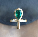 An emerald and diamond ankh ring with natural gemstones in a gold setting.