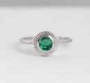 Emerald solitaire engagement ring with round green stone in 14k gold.