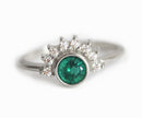 Emerald and diamond ring with green gemstone and diamond halo on gold band.