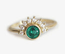 Emerald and diamond ring in 18k gold with green gem center and diamond halo.