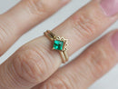 Close-up view of a princess cut emerald ring set with sparkling emeralds.