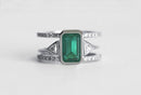 Emerald ring set with green gem centerpiece, diamond pave, and open band.